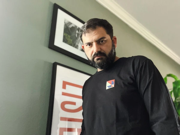 Dsum wearing a black shirt, looking directly at the camera with a neutral expression