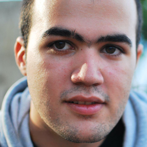 Dsum wearing a black shirt, looking directly at the camera with a neutral expression