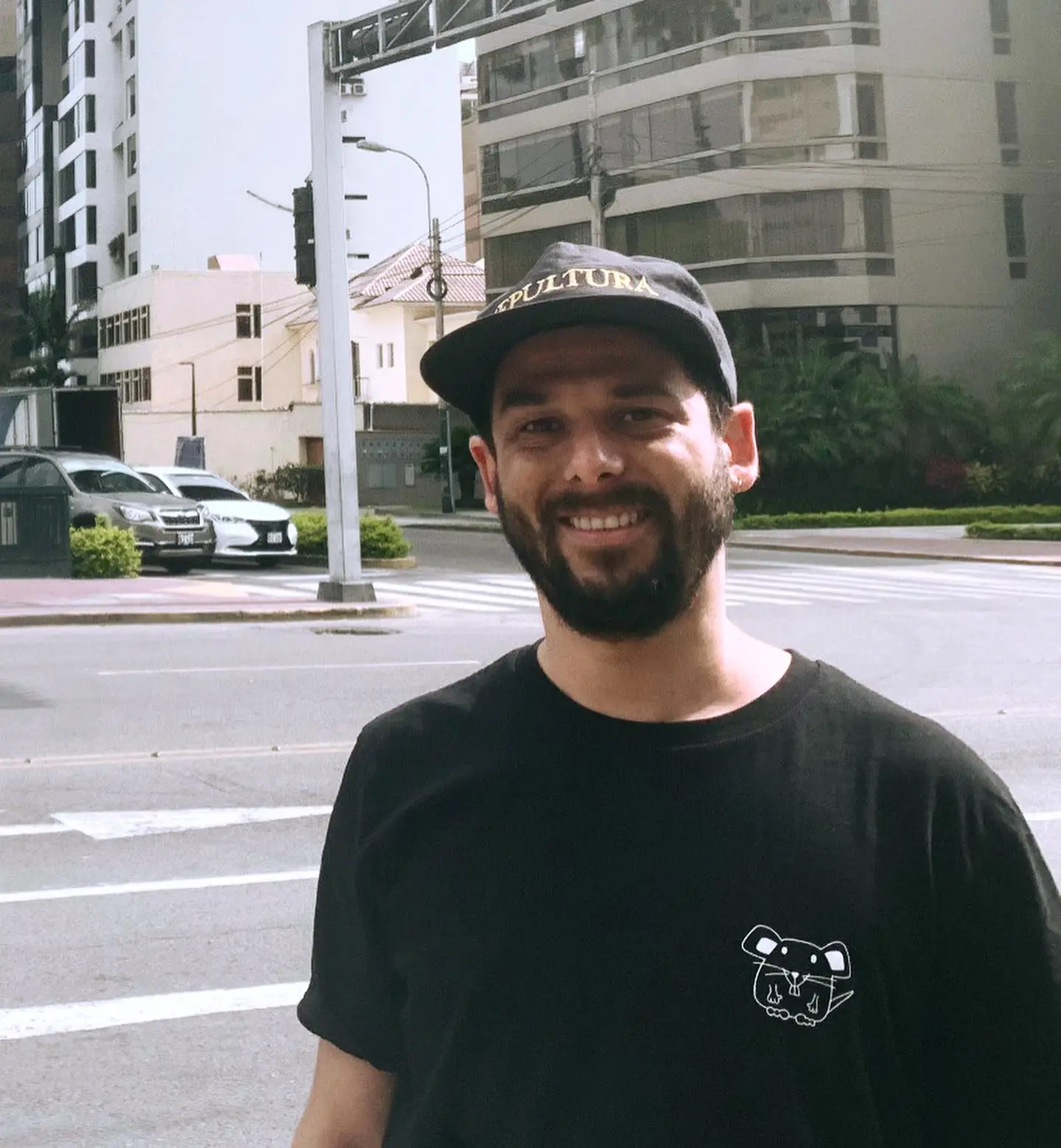 Vandelklang in a black shirt and hat stands in the middle of a street, surrounded by empty road and buildings.